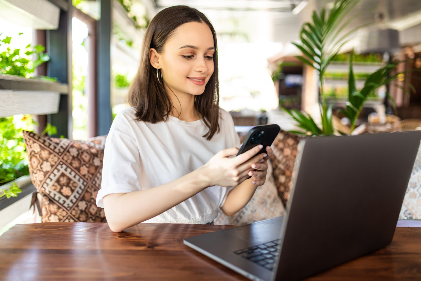 Woman checking her phone while using a laptop