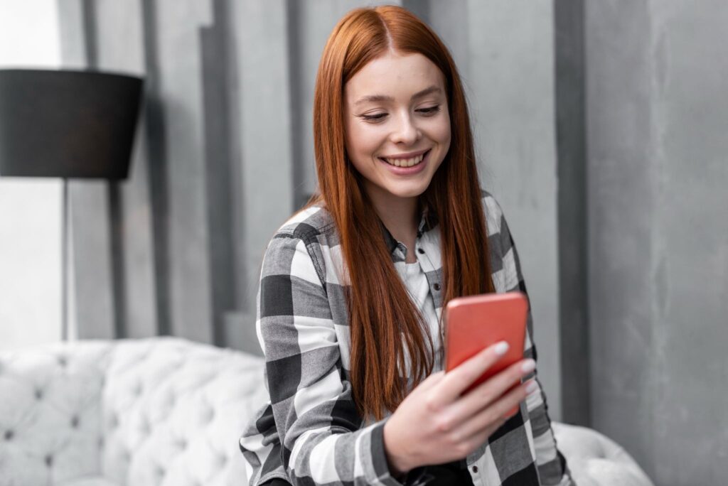 A girl smiling while using her phone